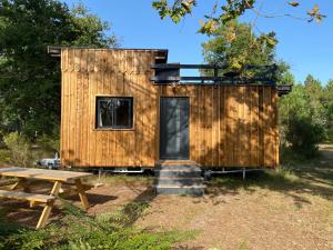 a wooden cabin with a picnic table and a bench at Camping la Kahute - Tiny House au coeur de la fôret in Carcans