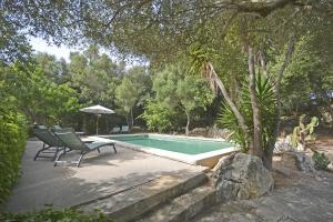 una piscina con dos sillas y una sombrilla en Es Romegueral, en Artà
