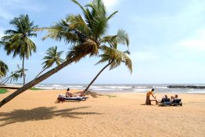 a group of people sitting on beach chairs under palm trees at Sun Star Villa Negombo in Daluwekotuwa