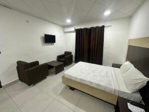 Habitación hospitalaria con cama, sillas y TV en hotel Brazza, en Brazzaville