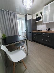 a kitchen with a table and white chairs in a room at Квартира с гостиничным сервисом в центре Петропавловска in Petropavlovsk