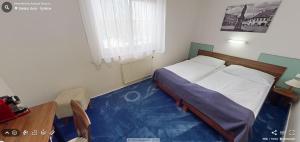 1 dormitorio con 1 cama y suelo azul en Hotel Selsky Dvur en Vyškov