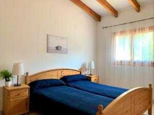 1 dormitorio con cama con sábanas azules y ventana en Casa Dorotea, en Son Serra de Marina
