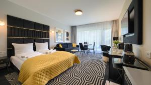 ein Hotelzimmer mit einem Bett mit einer gelben Decke in der Unterkunft Solny Resort, Sun & Snow in Kołobrzeg