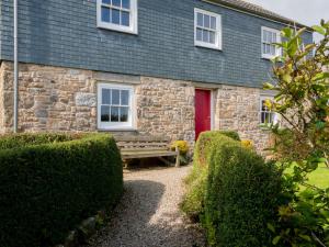 una casa de piedra con una puerta roja y un banco en Rosecott en St Ives