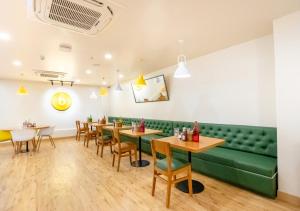 a dining room with a green couch and tables and chairs at Bloom Hotel - HSR Layout Sec 6 in Bengaluru