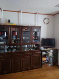 a large wooden cabinet with glass doors and a tv at 玉川温泉の湯治に最適な宿　鳳凰館 in Senboku