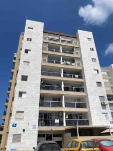 un edificio alto con coches estacionados frente a él en יחידת דיור ברמת בית מלון עם ממד, en Ashdod