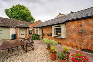 a brick house with a patio with a bench at The Granary at Pannels Ash Farm in Sudbury