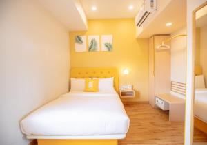 a bedroom with a white bed and a yellow wall at Bloom Hotel - HSR Layout Sec 6 in Bengaluru