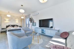 ein Wohnzimmer mit einem Sofa, Stühlen und einem TV in der Unterkunft Laudato XXL DELUXE in Turanj