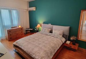 1 dormitorio con cama y pared verde en Chic 2BR Bright Penthouse with Open Wood Staircase, en Atenas