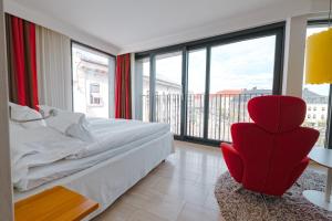 um quarto com uma cadeira vermelha e janelas grandes em Avalon Hotel em Gotemburgo