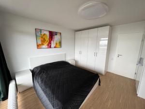Schlafzimmer mit einem schwarzen Bett und weißen Schränken in der Unterkunft Apartment Domblick in Köln