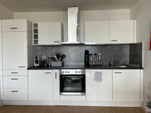 a white kitchen with white cabinets and an oven at Apartment Domblick in Cologne