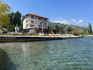 a building on the shore of a river with chairs at Hotel Victoria in Pogradec