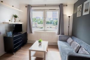a living room with a blue couch and a window at Olympic apartment - Stratford in London