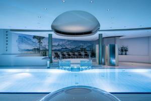 a pool with chairs and a table in a building at Alpenhof Murnau in Murnau am Staffelsee