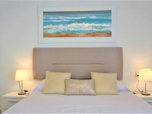 - une chambre avec un lit blanc et un tableau au-dessus dans l'établissement La perla del mar 1, à Son Servera