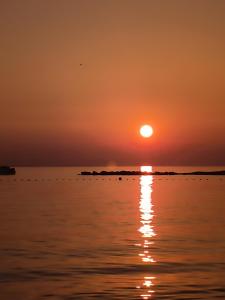 a sunset over the water with the sun in the sky at Apartments Orlić in Povljana