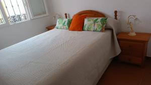 Una cama blanca grande con una almohada naranja. en Villa Luz Deluxe, en Mazagón
