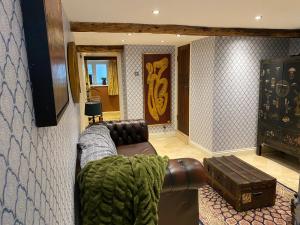 Linden Retreat في Brimscombe: غرفة معيشة مع أريكة جلدية وطاولة