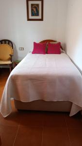 1 dormitorio con cama blanca y almohadas rosas en Villa Luz Deluxe, en Mazagón