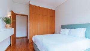 een slaapkamer met een groot bed en een houten kast bij Mouzinho Downtown 2BR w/ parking by LovelyStay in Porto