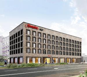 a large brick building with a red sign on it at Hampton By Hilton Szczecin East in Szczecin
