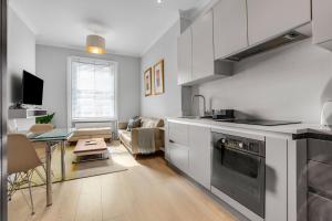 a kitchen and living room with a table and a couch at Phaedrus Living: South Kensington Luxury Flat in London