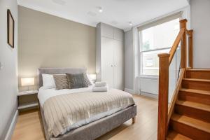 a bedroom with a bed and a window and stairs at Phaedrus Living: South Kensington Luxury Flat in London