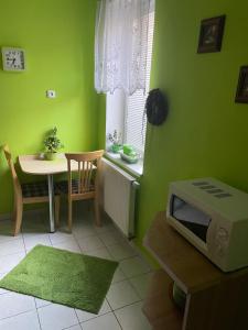 een groene kamer met een tafel en een magnetron bij Ubytování u Medvěda in Rokytnice v Orlických Horách