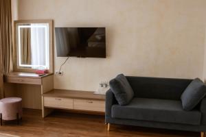 a living room with a couch and a television on the wall at Graff Hotel in Dnipro