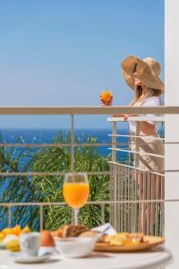 a woman sitting on a balcony with a glass of orange juice at Florasol Residence Hotel - Dorisol hotels in Funchal