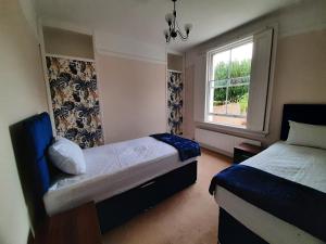 een slaapkamer met 2 bedden en een raam bij Wokingham - Central 2 beds home with parking in Wokingham