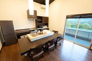 una cucina con ampia isola con sedie e ampia finestra di トワイライトヒルズ Twilight Hills a Motobu