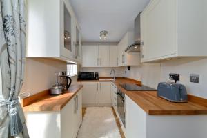 倫敦的住宿－Modern House near Canary Wharf, Excel, Greenwich，厨房配有白色橱柜和蓝色电器