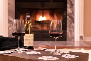 two glasses of wine on a table with a fireplace at Villa Signor in Norwich