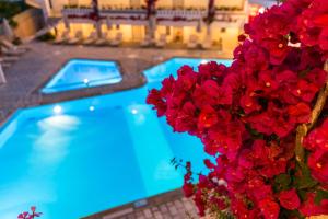 a blue swimming pool with red flowers next to it at Ariadne Hotel in Platanes