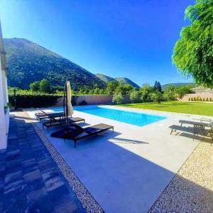 a villa with a swimming pool with mountains in the background at Villa Vita in Mostar