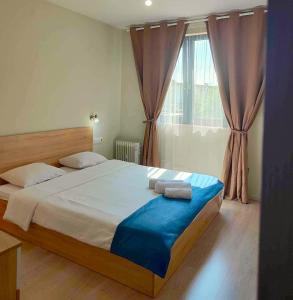 a bedroom with a large bed with blue sheets and a window at City Residence Apartments Sofia in Sofia