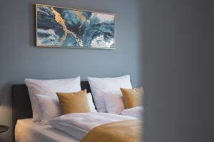 1 cama con almohadas blancas y una pintura en la pared en DELUXE APARTMENT 2 Schlafzimmer - kostenlos Parken - Messe Flughafen - Balkon - Netflix, en Leinfelden-Echterdingen