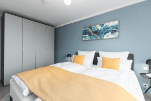 una camera da letto con un grande letto bianco con cuscini arancioni di DELUXE APARTMENT 2 Schlafzimmer - kostenlos Parken - Messe Flughafen - Balkon - Netflix a Leinfelden-Echterdingen