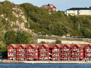 a large red building on a hill next to the water at Nydelig ferieleilighet på bryggekanten in Korshamn