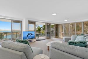 a living room with two couches and a flat screen tv at Oceanfront apartment on top of point Cartwright in Buddina