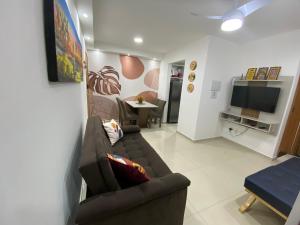 a living room with a couch and a tv at Apto em Condomínio Resort entre Ponta Negra e Cotovelo in Parnamirim