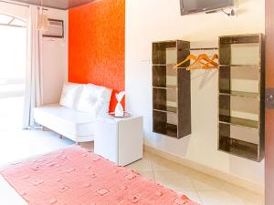 sala de estar con sofá blanco y pared de color naranja en VELINN Pousada Casa de Pedra Ilhabela, en Ilhabela