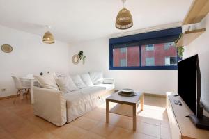 ein Wohnzimmer mit einem weißen Sofa und einem Fernseher in der Unterkunft Apartamento Lancelot in Puerto del Rosario