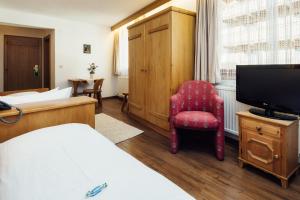 Habitación de hotel con cama, silla y TV en Hotel Komperdell, en Serfaus