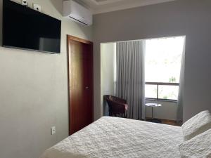 um quarto de hotel com uma cama e uma janela em Hospedagem Estação em Domingos Martins